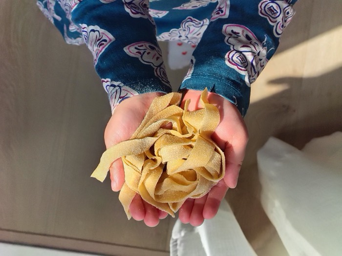 Two hands holding a nest of fresh egg tagliatelle