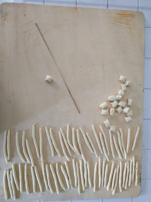 Fresh pasta being rolled and cut by hand on a wooden board