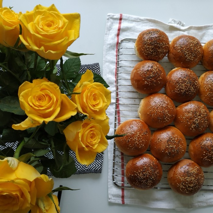 A tray of small glazed bread rolls with yellow roses