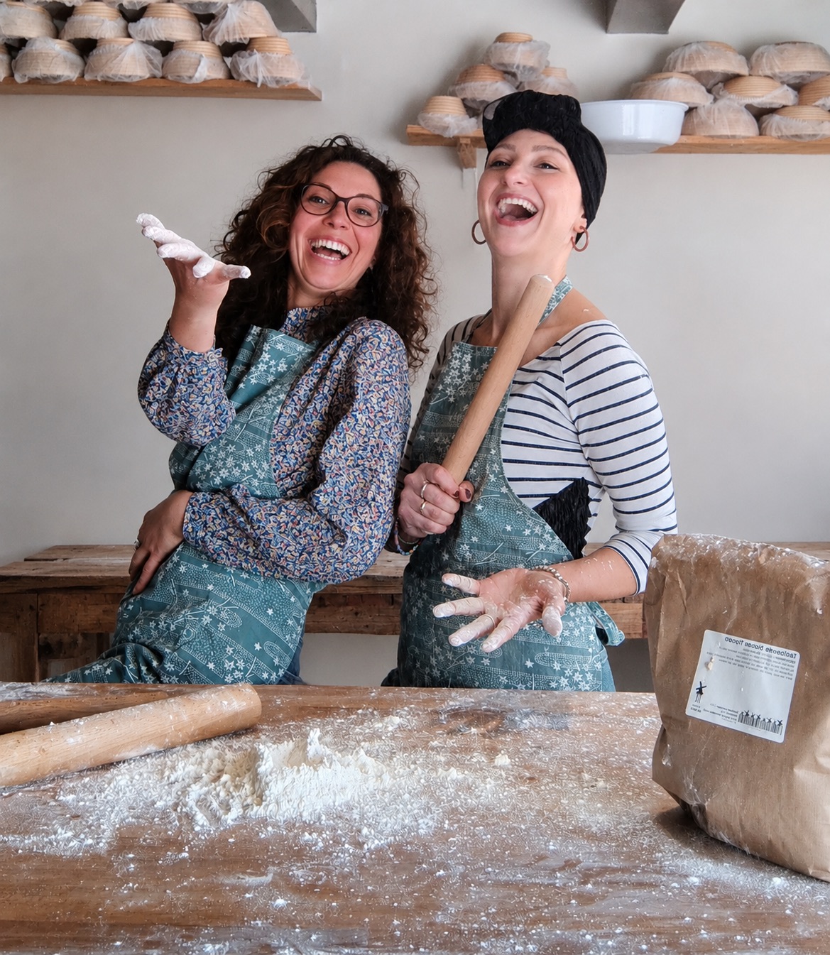 Raffa and Vale laughing with floury hands and a rolling pin at Molen de Roos